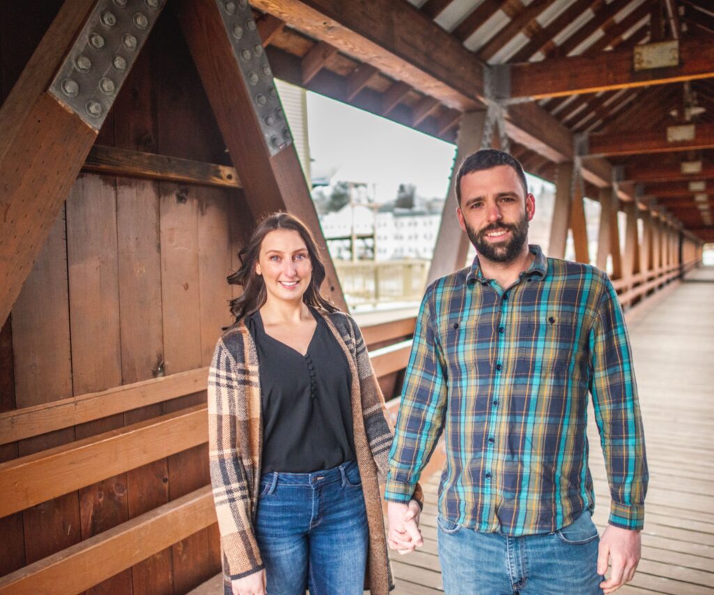 happy woman and man holding hands, standing inside a covered bridge