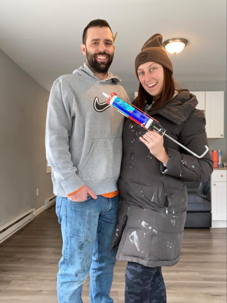 man and woman standing together. woman is holding a caulking gun.