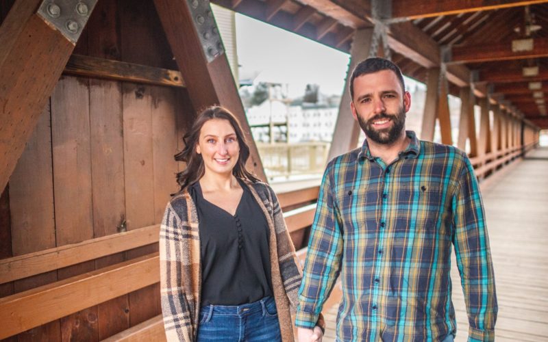 happy woman and man holding hands, standing inside a covered bridge